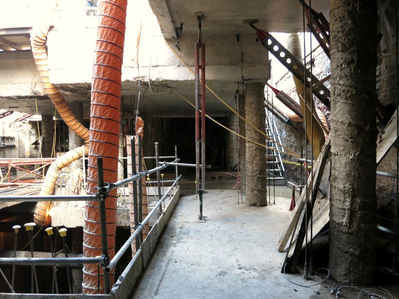 A lower floor under construction, with concrete piles, steel props and ventilation ducts.