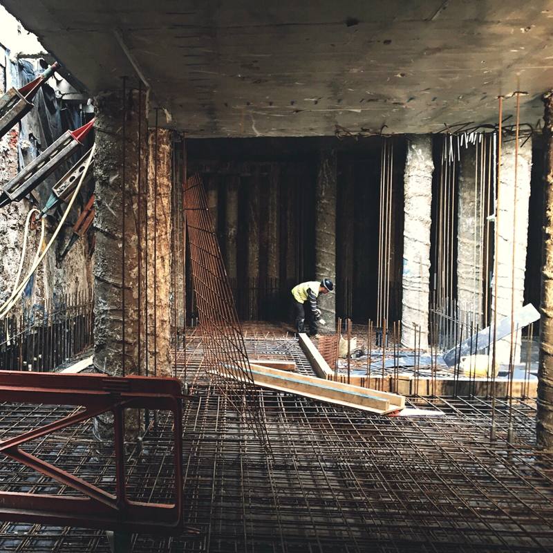 Steel reinforcement laid across a basement floor between the piled walls.