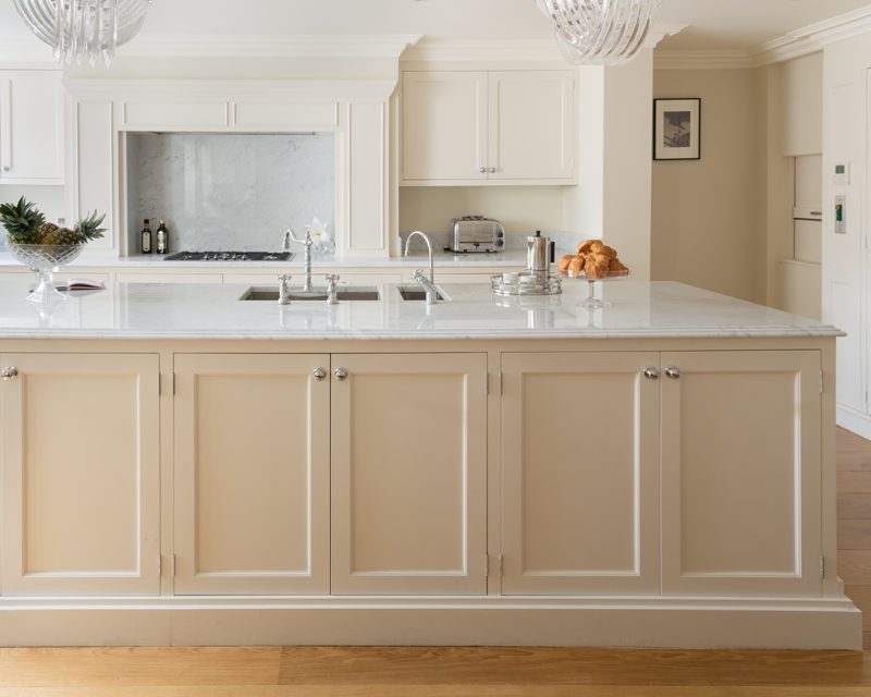 Kitchen with a marble topped island and glass pendant lights.