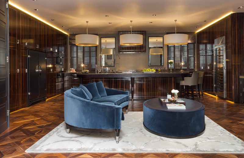 The kitchen and living floor of a finished Chelsea townhouse: macassar joinery, a long island and a blue sofa on parquet.